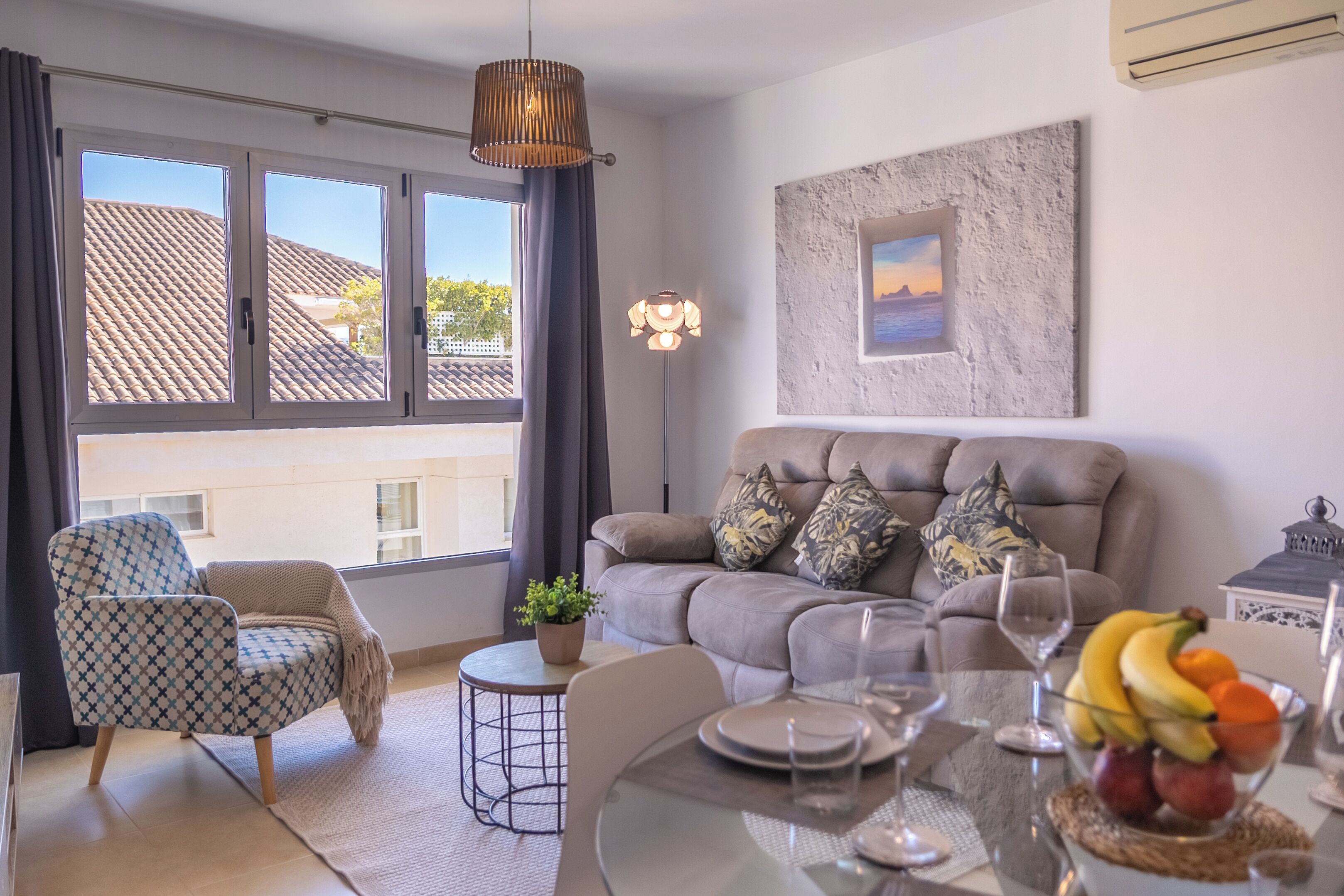 Un salon moderne comprenant un canapé, un fauteuil, une table à manger et une grande fenêtre avec des rideaux.