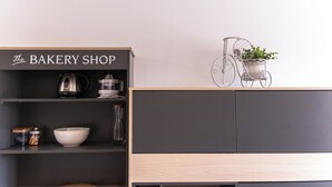 Uma cozinha compacta com cafeteira, uma tigela e um letreiro que diz 'The Bakery Shop'.