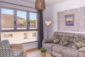 Ein Wohnzimmer mit einer Couch, einem Sessel und einer Topfpflanze.