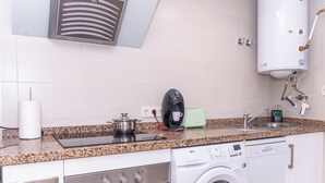 Uma cozinha com fogão, forno, máquina de lavar e aquecedor.