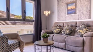 Uma sala de estar com sofá, poltrona, mesa de centro redonda e luminária de chão.