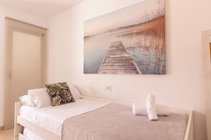 A bedroom with a bed, pillows, a blanket, and a painting of a pier. - Modern, centrally located, with private parking and an elevator   (Altea)