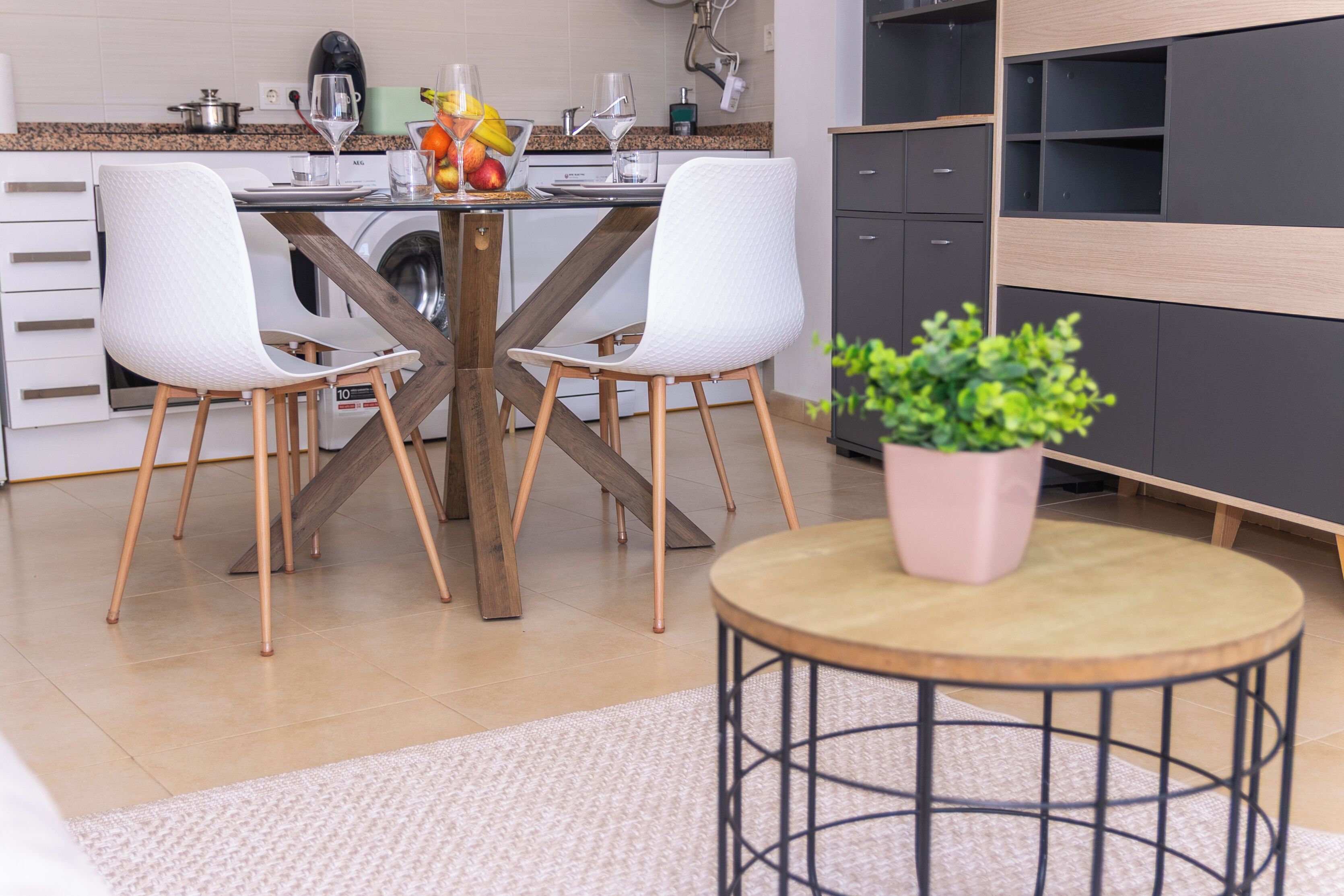 A modern kitchen with a dining table, chairs, and a potted plant.
