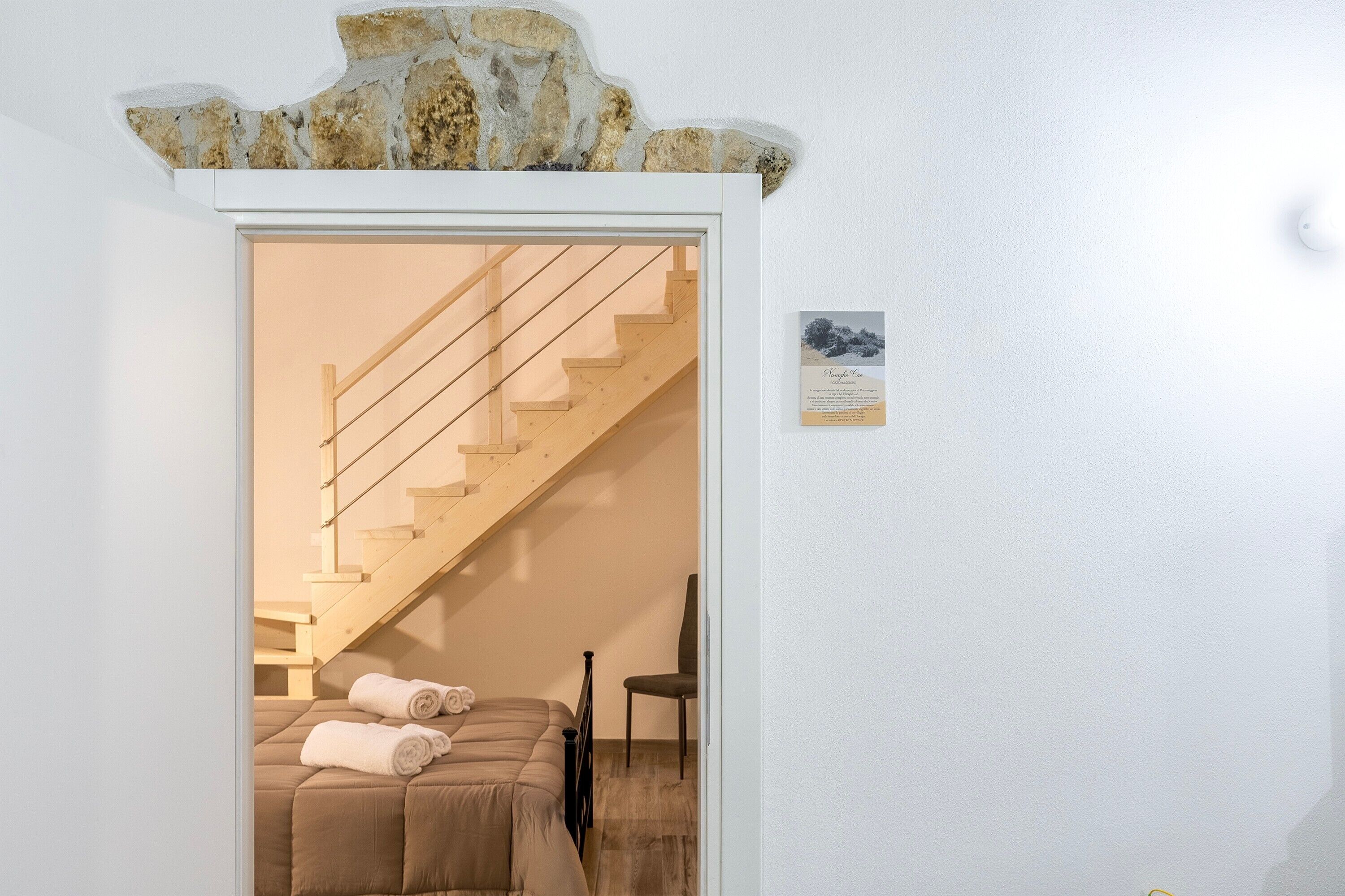 Ein Zimmer mit einem Bett, einem Sessel und einer Treppe, die zu einer weiteren Ebene führt.