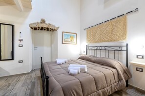Une chambre à coucher avec un lit, une porte, un luminaire fixé au mur et un tableau encadré.