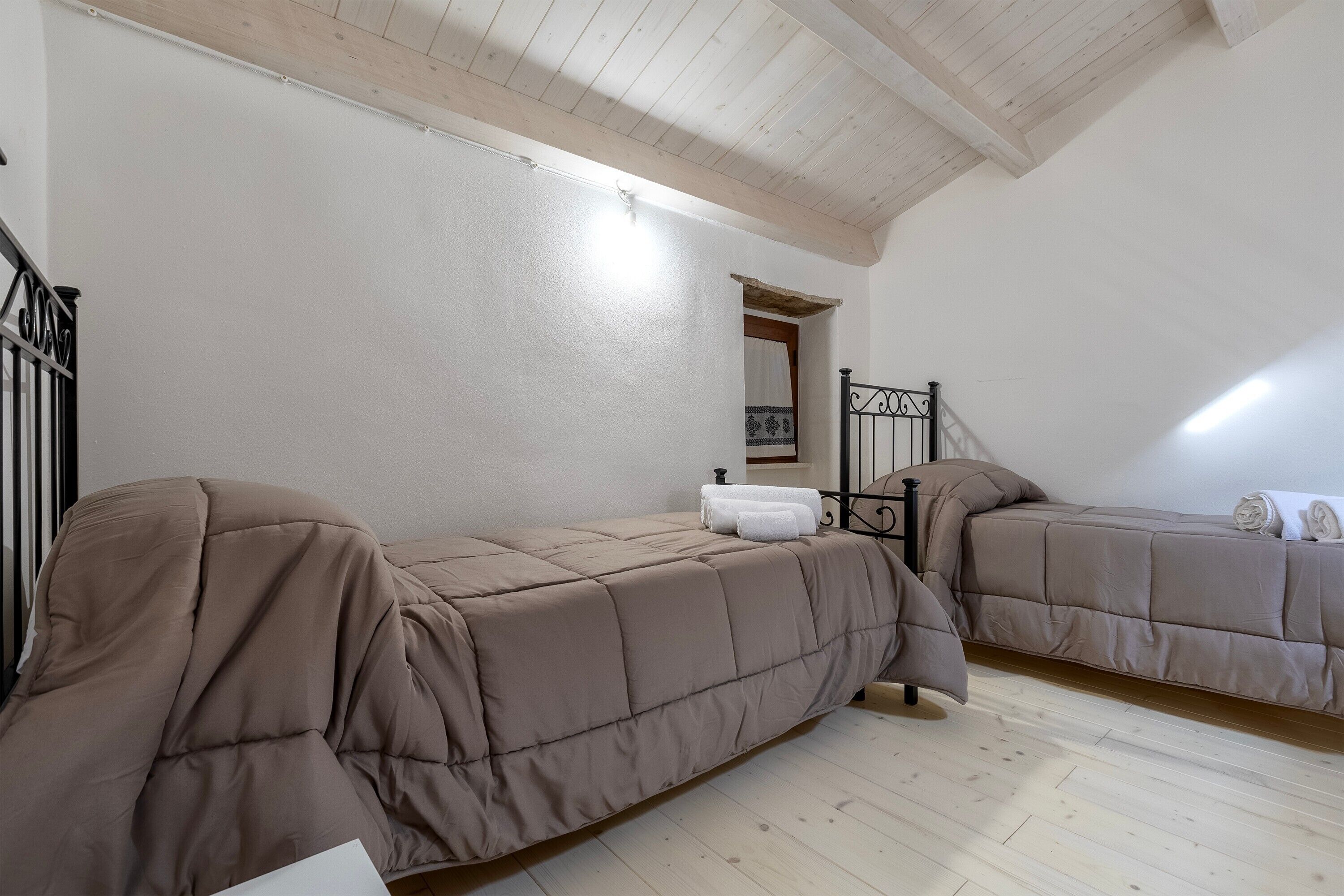 Un dormitorio con dos camas, suelo de madera, una escalera y un techo blanco.