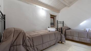 Un dormitorio con dos camas, suelo de madera, una escalera y un techo blanco.