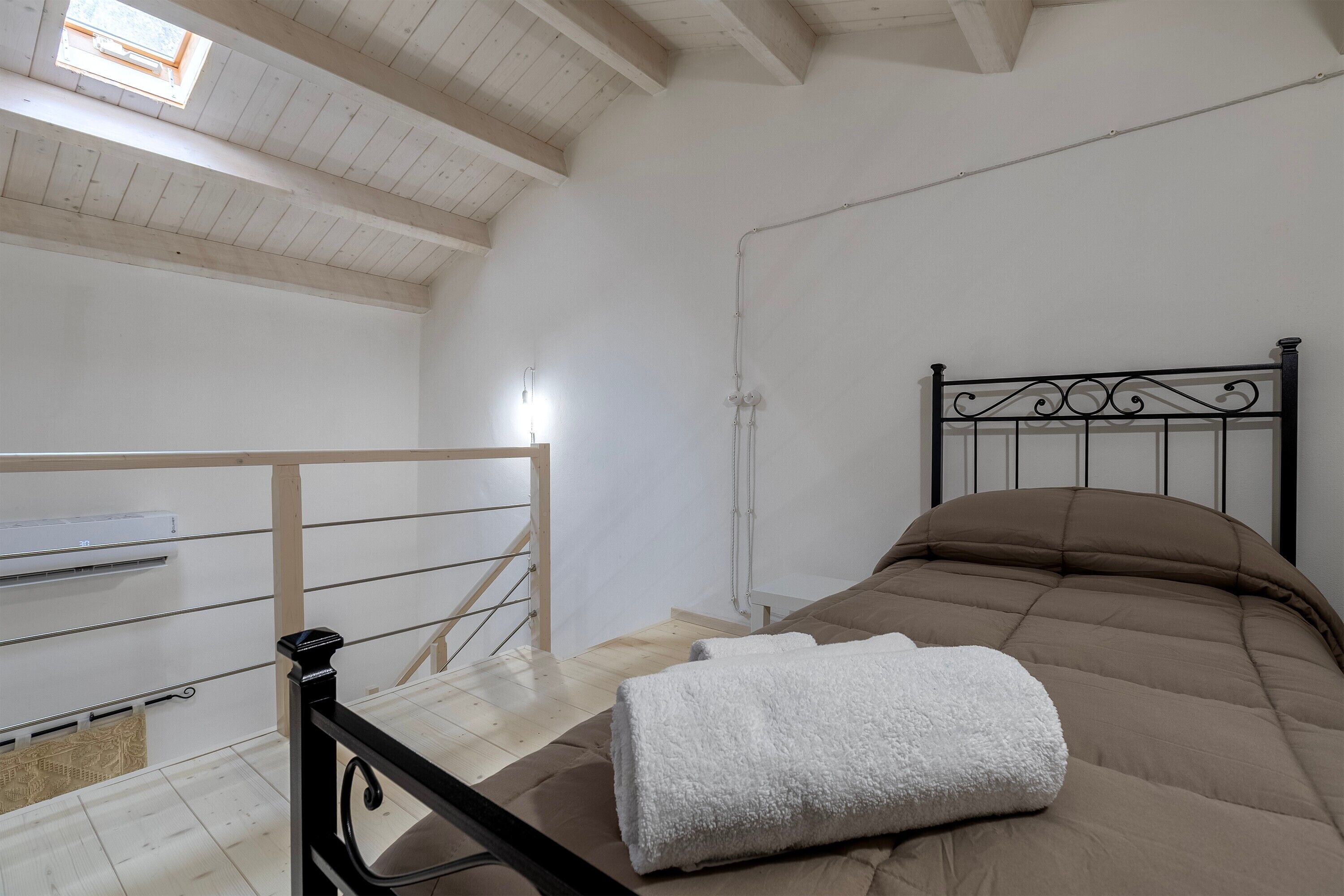 Ein Schlafzimmer mit einem Bett, einem Fenster und einer Treppe.