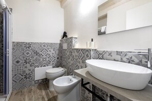 Une salle de bain avec un grand lavabo blanc, un bidet et des toilettes.