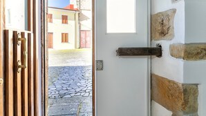 Une porte donnant sur un mur de pierre, une fenêtre et une vue sur une rue pavée.