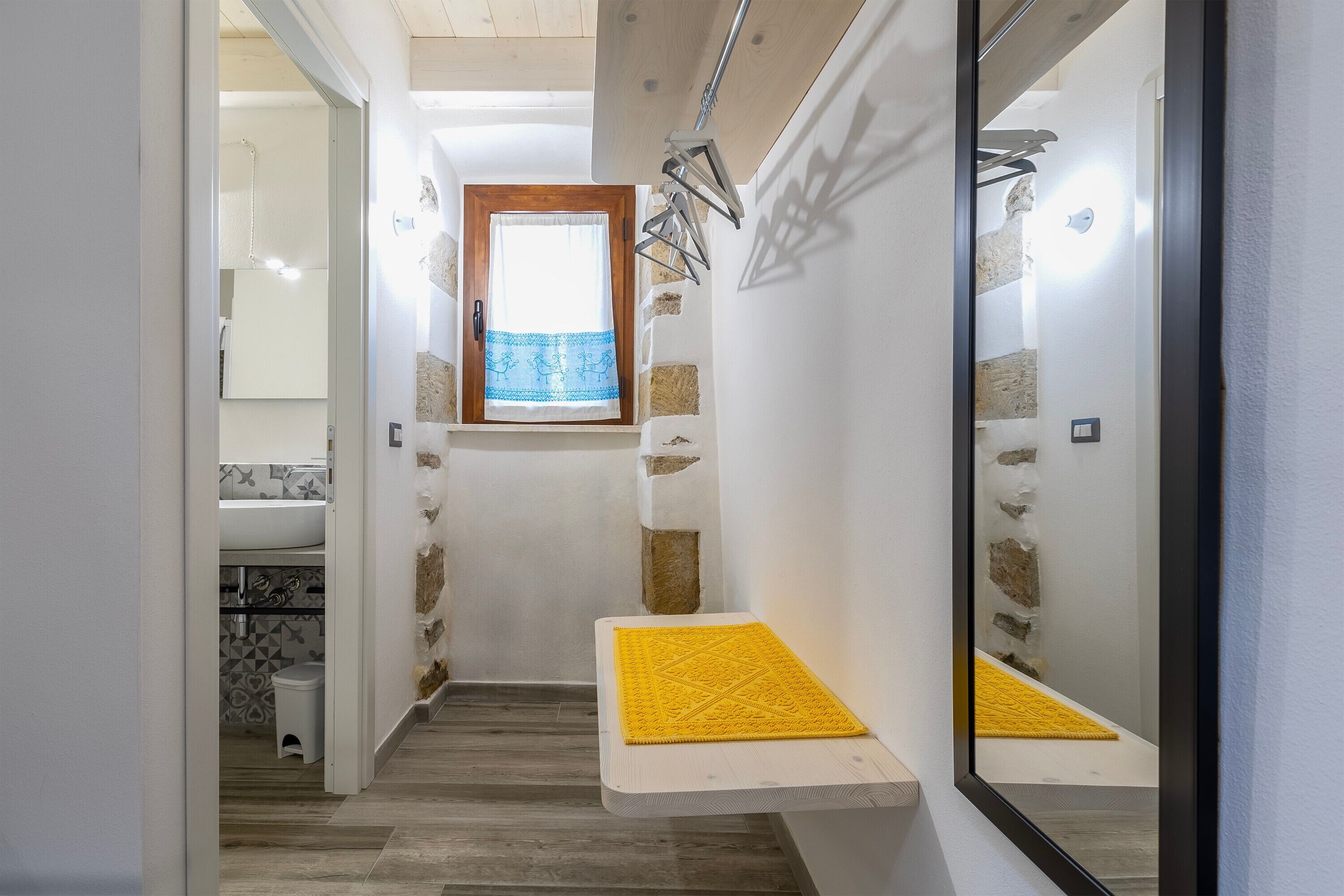 Ein schmales Badezimmer mit Dusche, Waschbecken und Fenster mit blauer Vorhang.