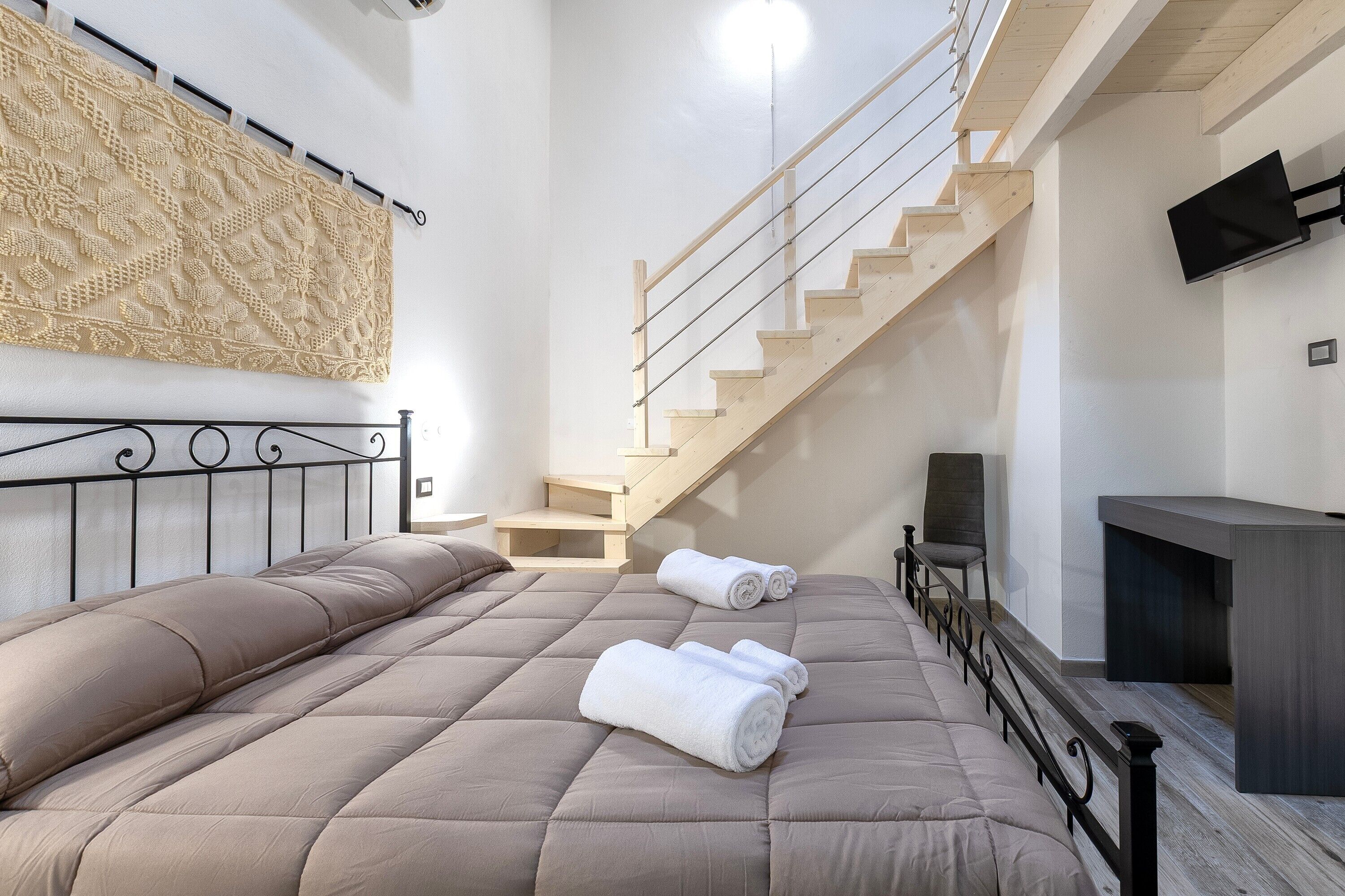 Ein Schlafzimmer mit einem Bett, einer Treppe, einem Fernseher und einem Wandbild.