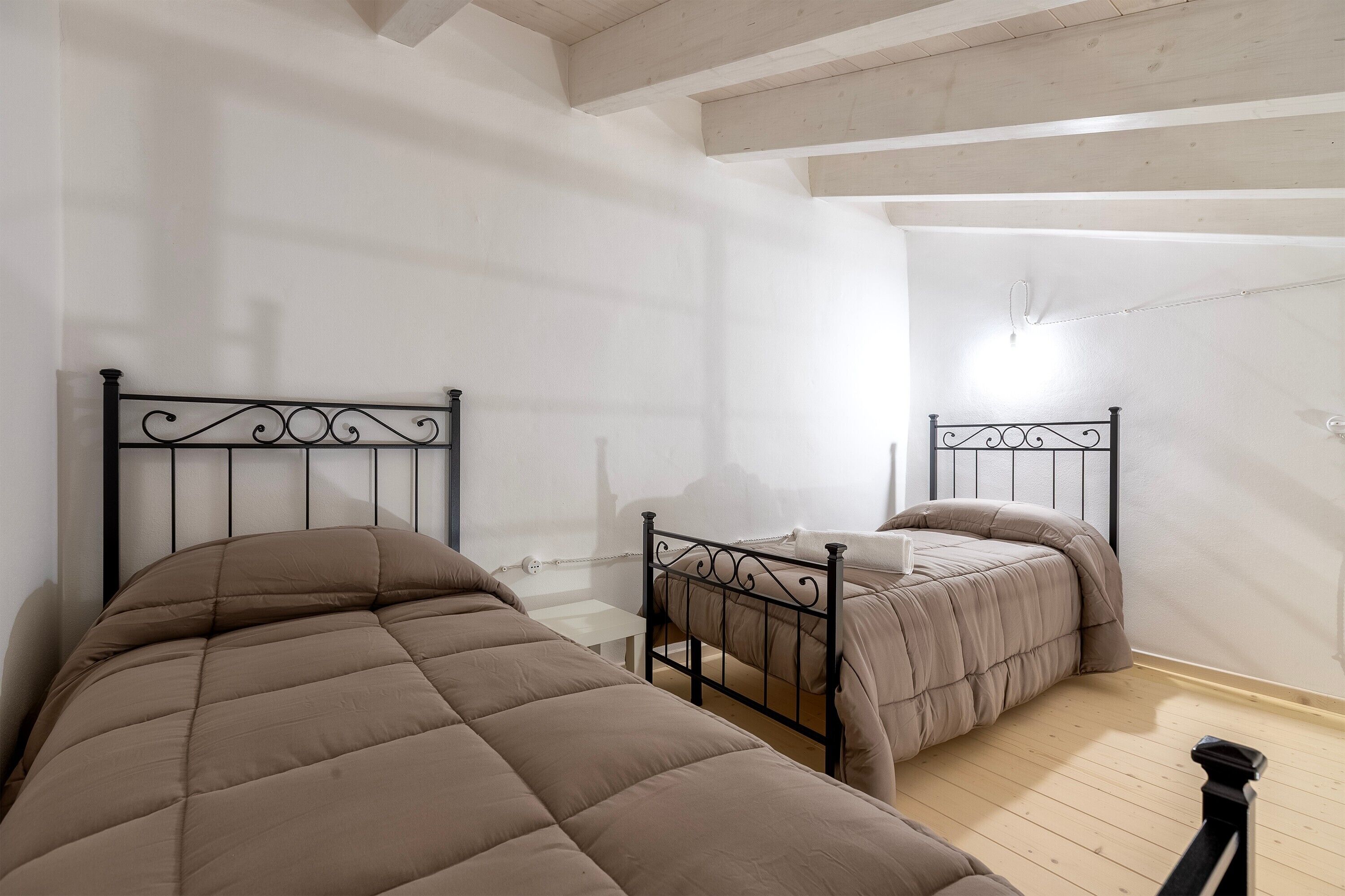 Ein Schlafzimmer mit zwei Betten, Holzboden und einer geneigten Decke.