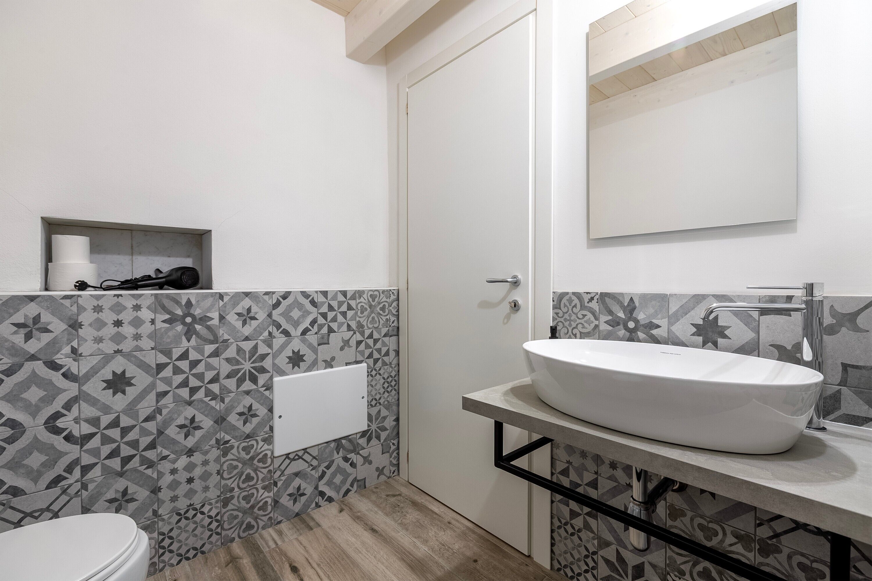 Ein Badezimmer mit einem weißen Waschbecken, einer Toilette und Fliesen mit Muster.