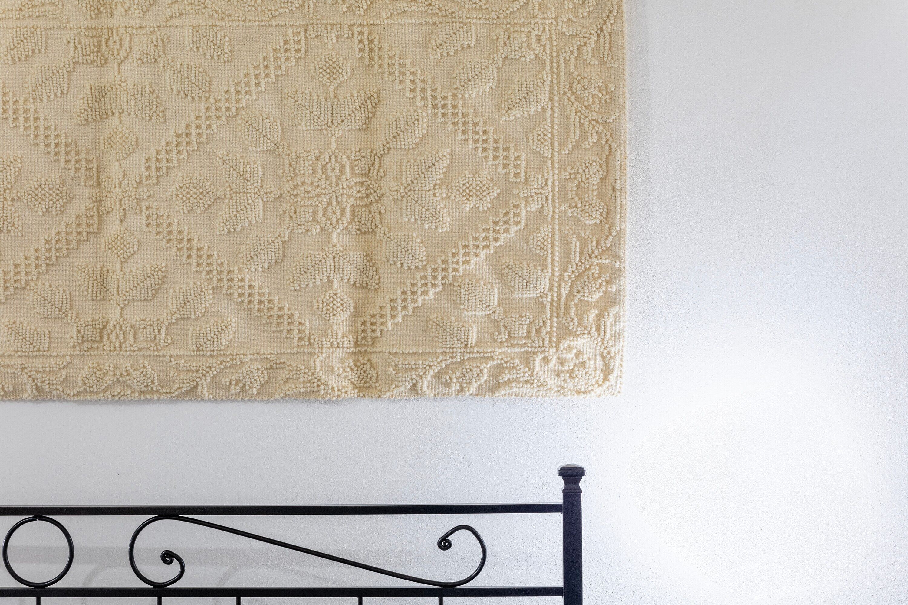 Una cama con cabecera de metal y un tapiz decorativo en la pared.