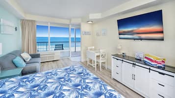Un dormitorio con una cama grande, un escritorio y vista al océano.