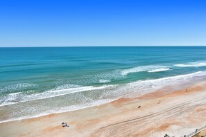 A beach with clear blue water and a sandy shore. - Oceanfront Studio Sleeps 4 | King + Sofa | Kitchen (Daytona Beach)