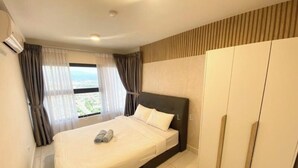 Ett hotellrum med en säng, en garderob och ett fönster med gardiner.