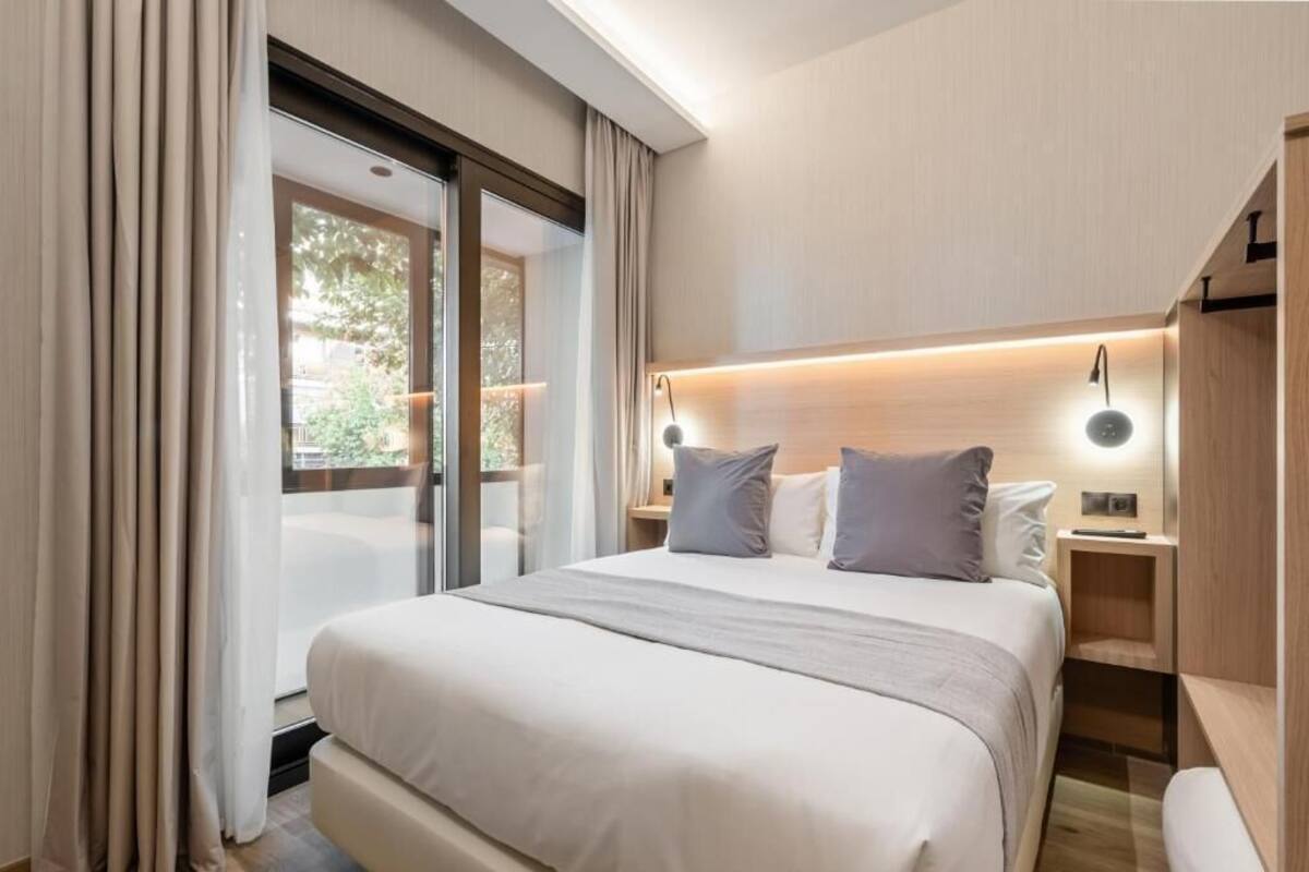 A modern bedroom with a large bed, a nightstand, and a built-in bench.