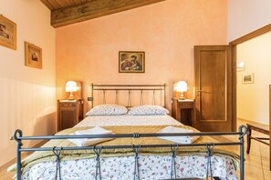 Ein Schlafzimmer mit einem Bett, zwei Nachttischen mit Lampen, einer Holztür und einem Bild an der Wand.