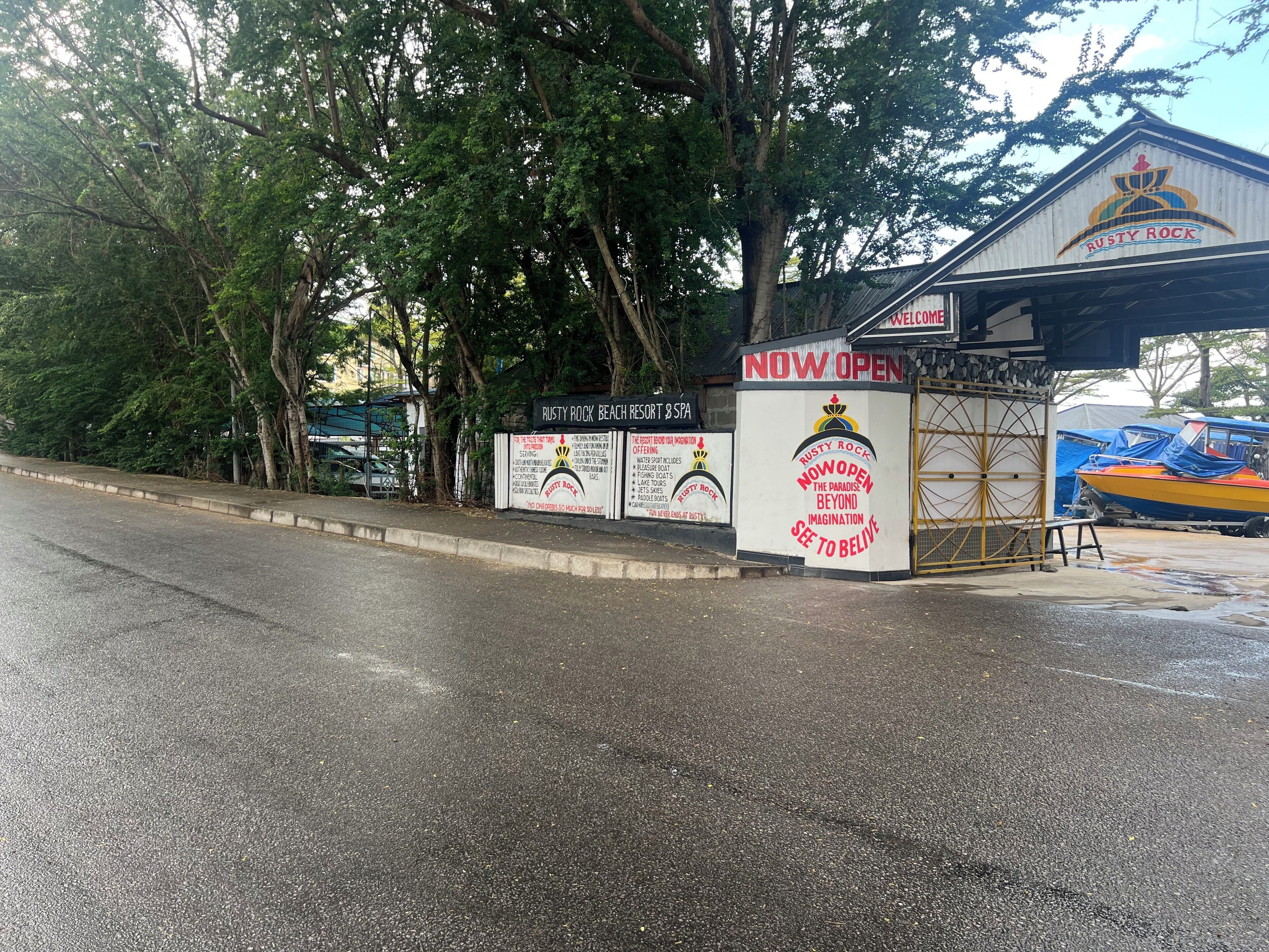 Un panneau indiquant un complexe hôtelier de bord de mer, avec les inscriptions « Rusty Rock Beach Resort & Spa » et « OUVERT MAINTENANT », ce qui signifie que le complexe est en activité.