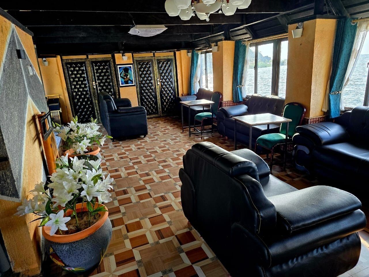 Um quarto com piso estampado, assentos em couro preto, uma mesa e um vaso com planta.