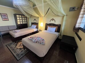 A hotel room with two beds, a sofa, a patterned rug, and a decorative wall piece.