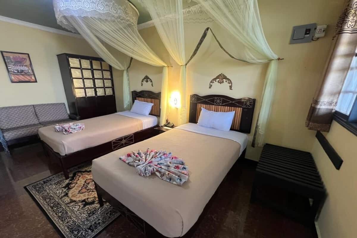 A hotel room with two beds, a sitting area, and a traditional design.
