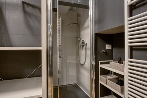 Ein modernes Badezimmer mit einer Duschkabine, integrierten Ablagen und einem Handtuchhalter.