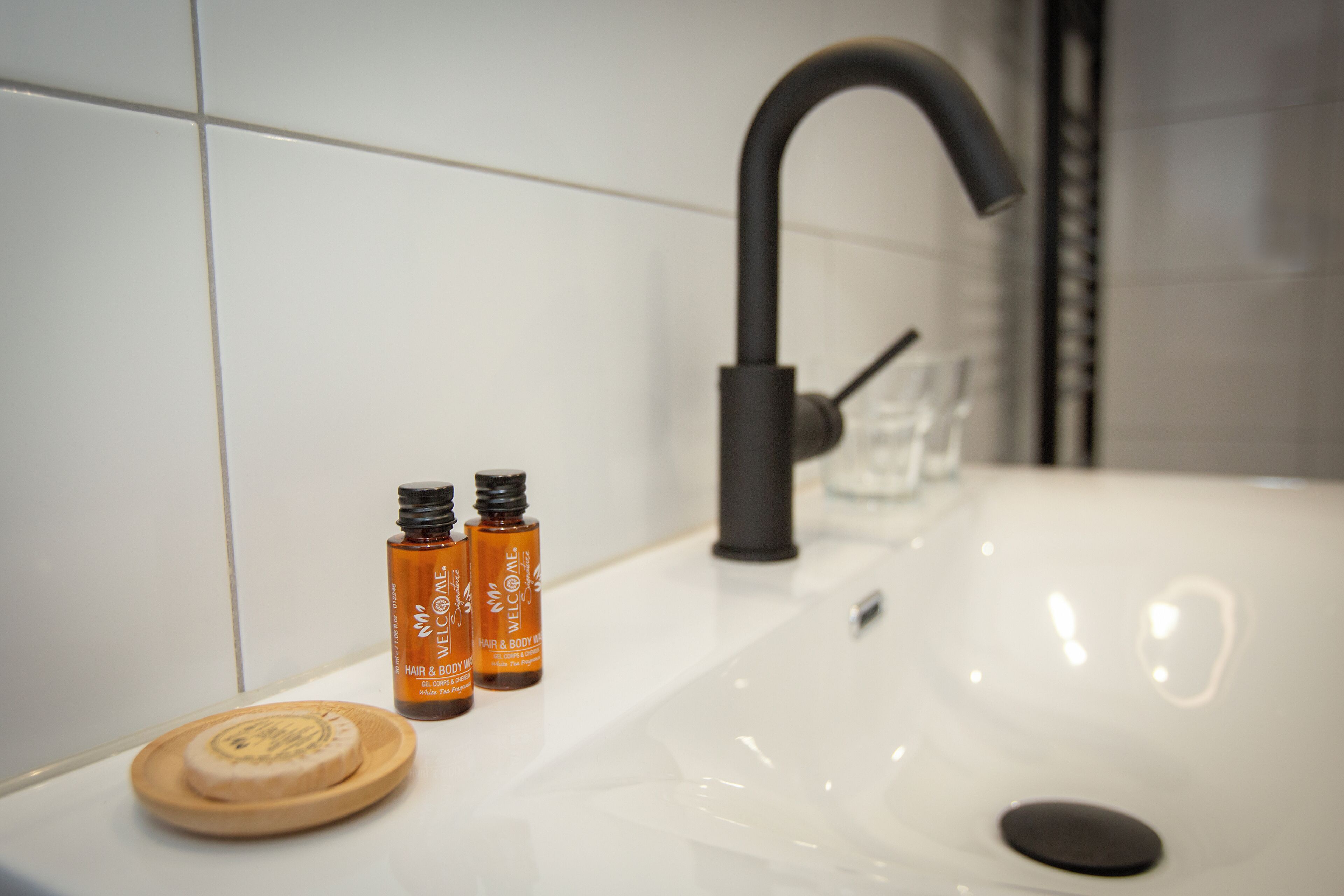 A bathroom sink with two bottles of hair and body wash, a soap dish, and a faucet.
