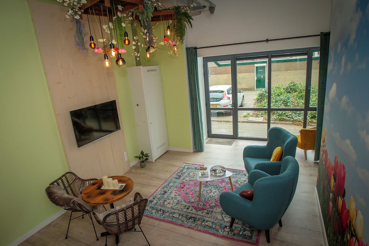 Una sala de estar con televisión, sofá, mesa de comedor y una alfombra estampada.