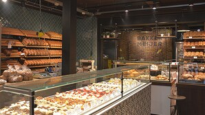 Une boulangerie où l’on peut admirer une variété de produits de boulangerie, avec un mur en briques et des guirlandes lumineuses suspendues.