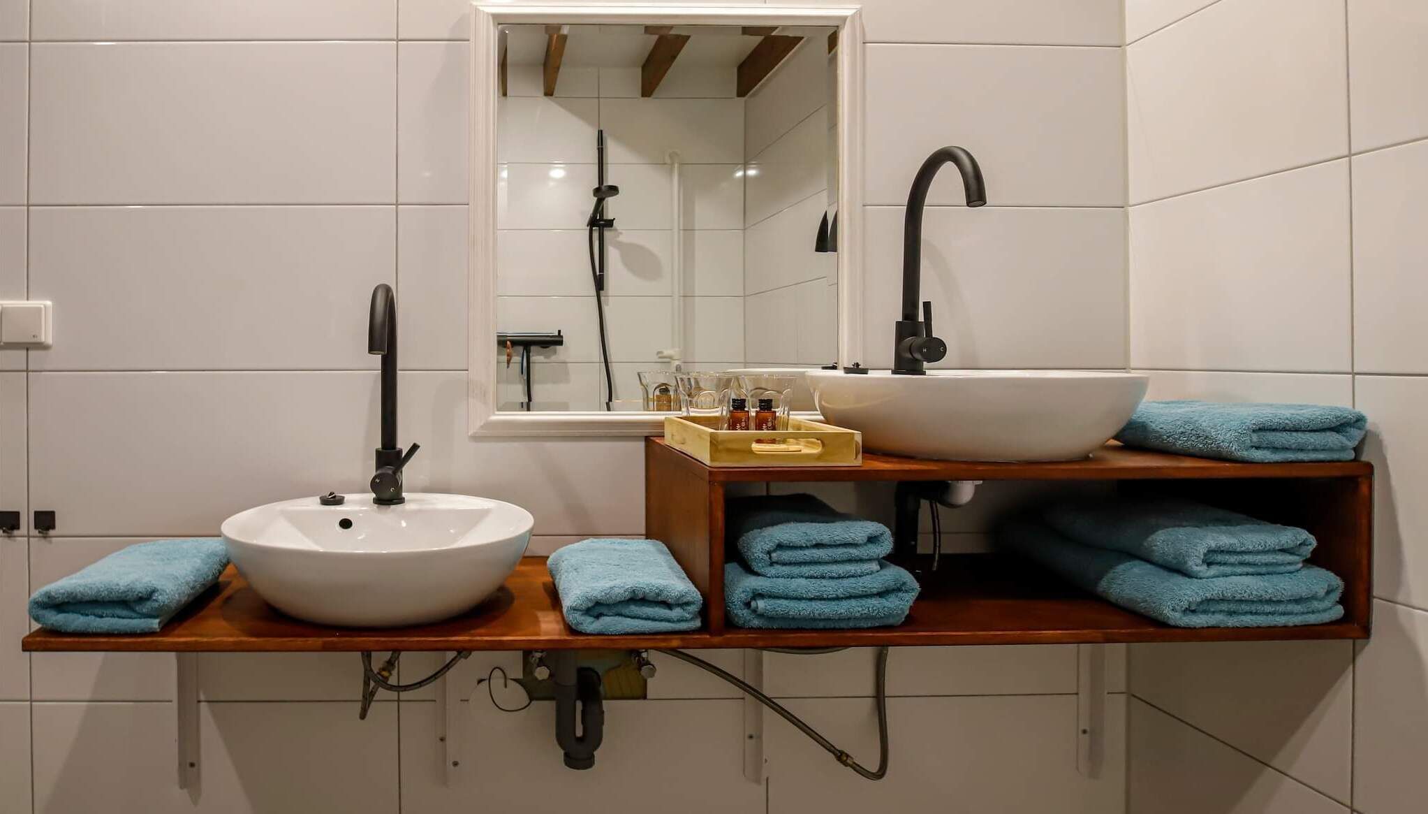 A bathroom with two sinks, a mirror, and a towel rack with folded towels.