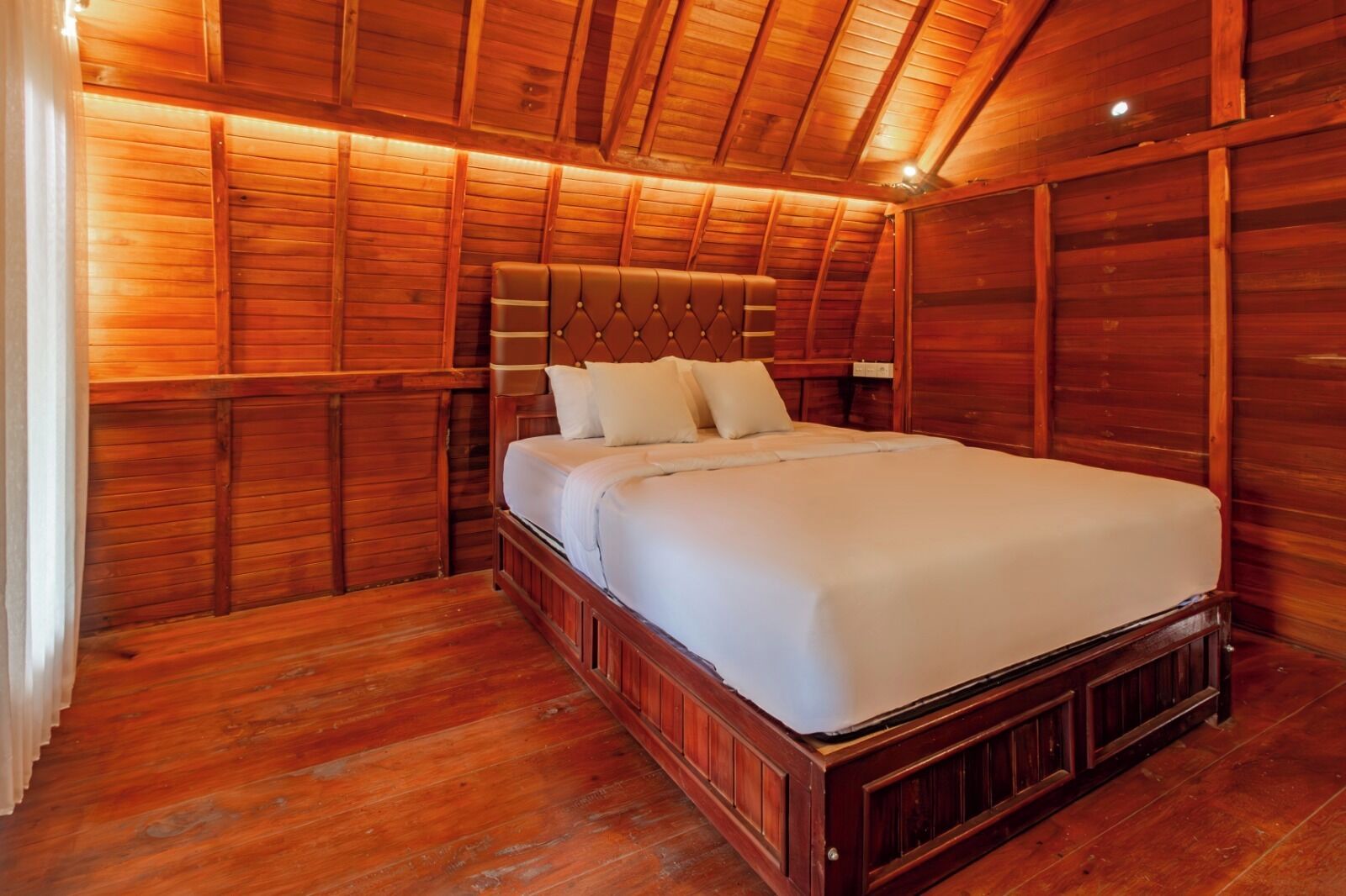 Un dormitorio con paneles de madera, cama, suelo de madera y techo inclinado.