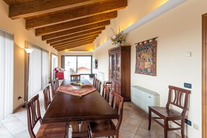 A dining area with a long wooden table, chairs, and a cabinet. - Panoramic Apartment near Gubbio (Sigillo)