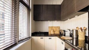 Une cuisine moderne équipée d’un four encastré, d’une cuisinière et d’une fenêtre avec des stores.