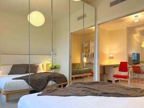 Een moderne hotelkamer met een bed, nachtkastje en een bureau met stoel.