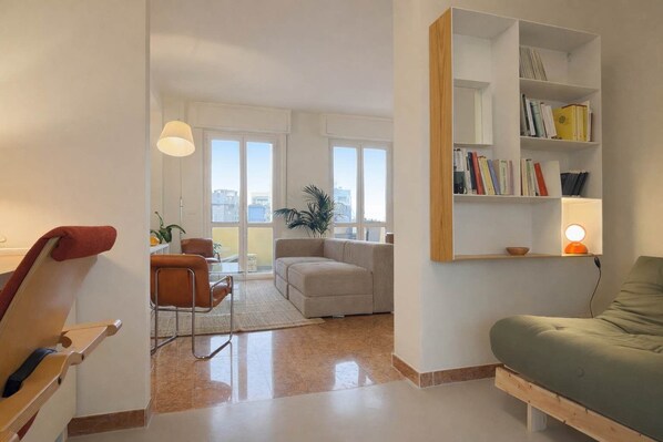 Een moderne woonkamer met een bank, een fauteuil, een bijzettafeltje en een boekenkast.