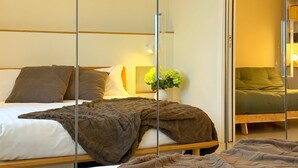 A hotel room with a bed, a bedside table with a vase of flowers, and a mirror reflecting the room. - Casa Matteo, panorama 20 min to Duomo (Milano)