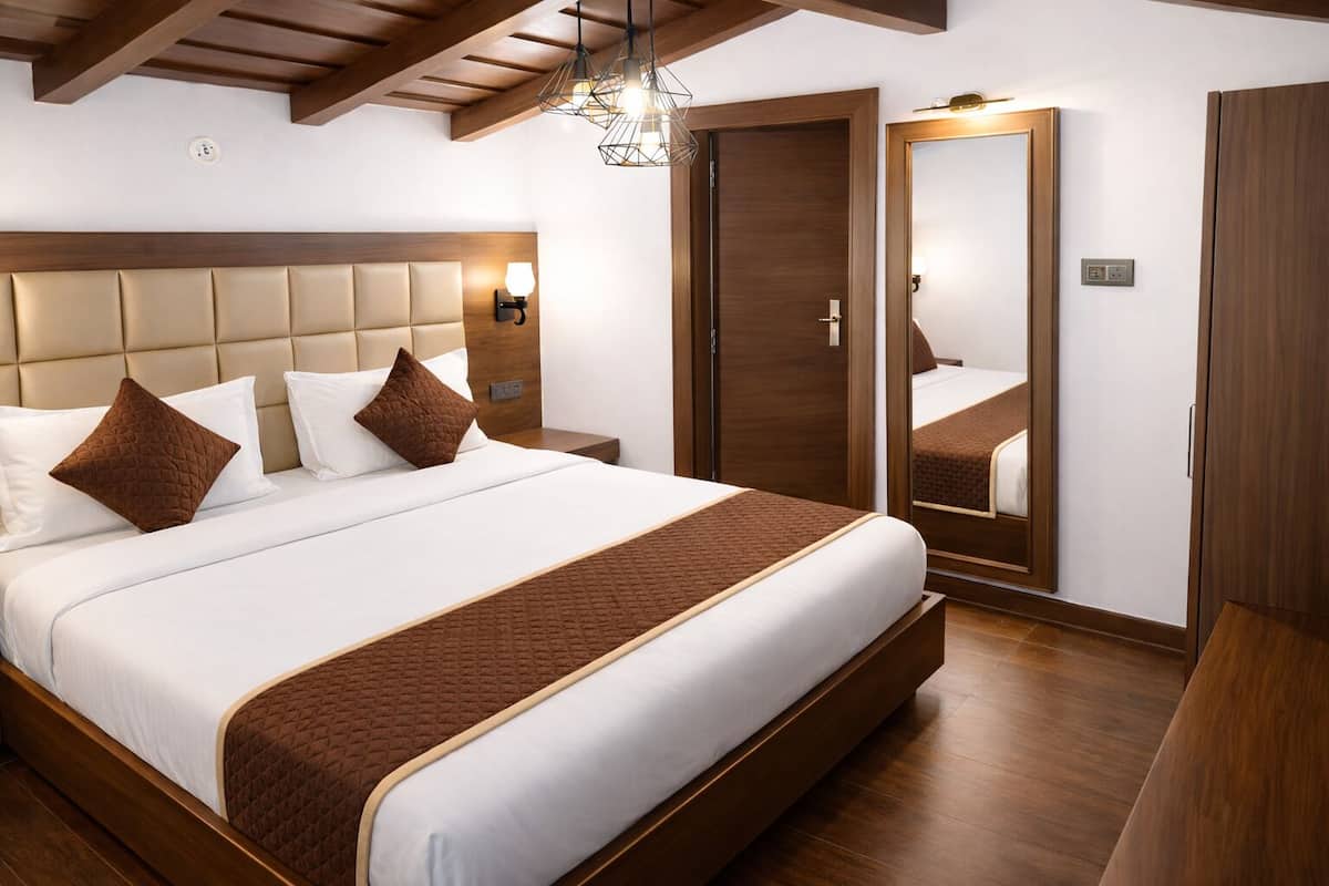 Ein Hotelzimmer mit einem großen Bett, einem Holzkopfstück, Nachttischlampen, einem Kleiderschrank und einem Spiegel.