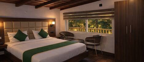 Un dormitorio con una cama grande, una mesita de noche, una silla, un armario y una ventana con vistas a árboles.