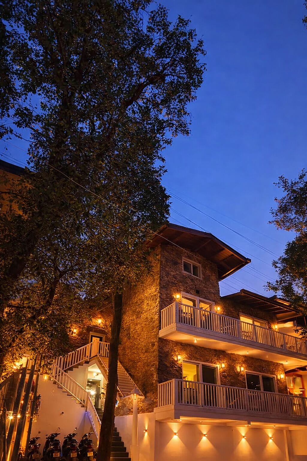 A multi-story building with a stone facade, a balcony on the second floor, and a staircase leading to the entrance.