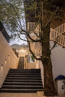 Una escalera que lleva a un edificio, con un árbol en primer plano.