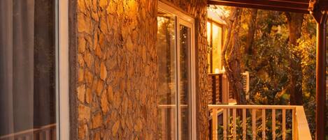 A stone exterior wall with a wooden deck and a pergola.