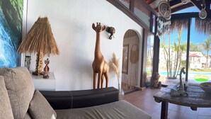 Une chambre avec vue sur la piscine, meublée en bois et agrémentée de diverses sculptures d’animaux.