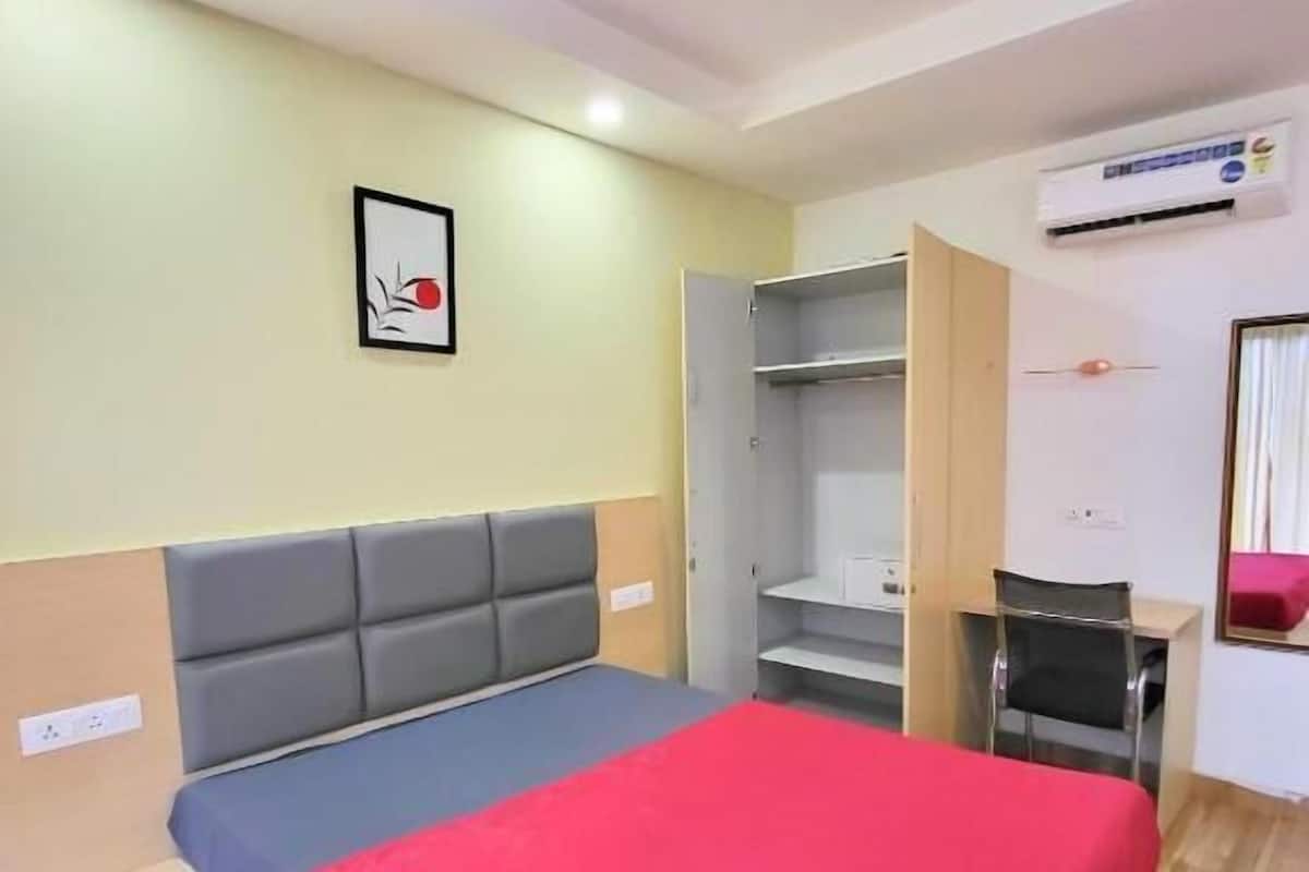 A bedroom with a bed, a desk, and a wardrobe.