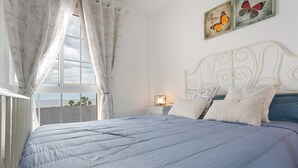 Une chambre à coucher avec un lit, des rideaux, une table de chevet, une lampe et des décorations murales représentant des papillons.
