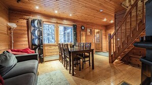 A cozy cabin interior with a wooden dining table, chairs, a sofa, and a staircase. - Snow Lodge Levi Center 8B by Aavalevi (Levi)