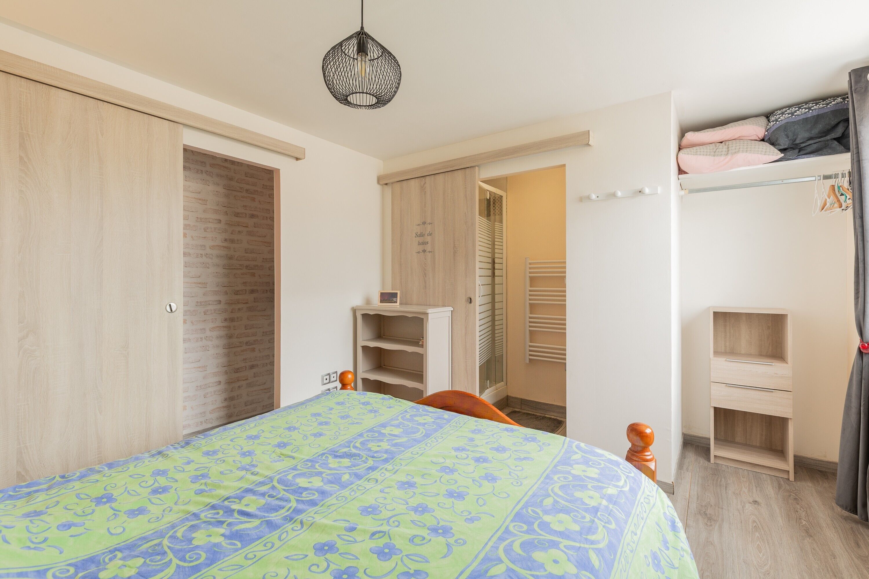 A bedroom with a bed, a wardrobe, a bedside table, a lamp, and a closet.