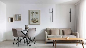 A modern living room with a dining area, a sofa, a coffee table, and wall-mounted decor. - By Edom - דירה נוף מטריף לים במתחם סי סייד (Eilat)